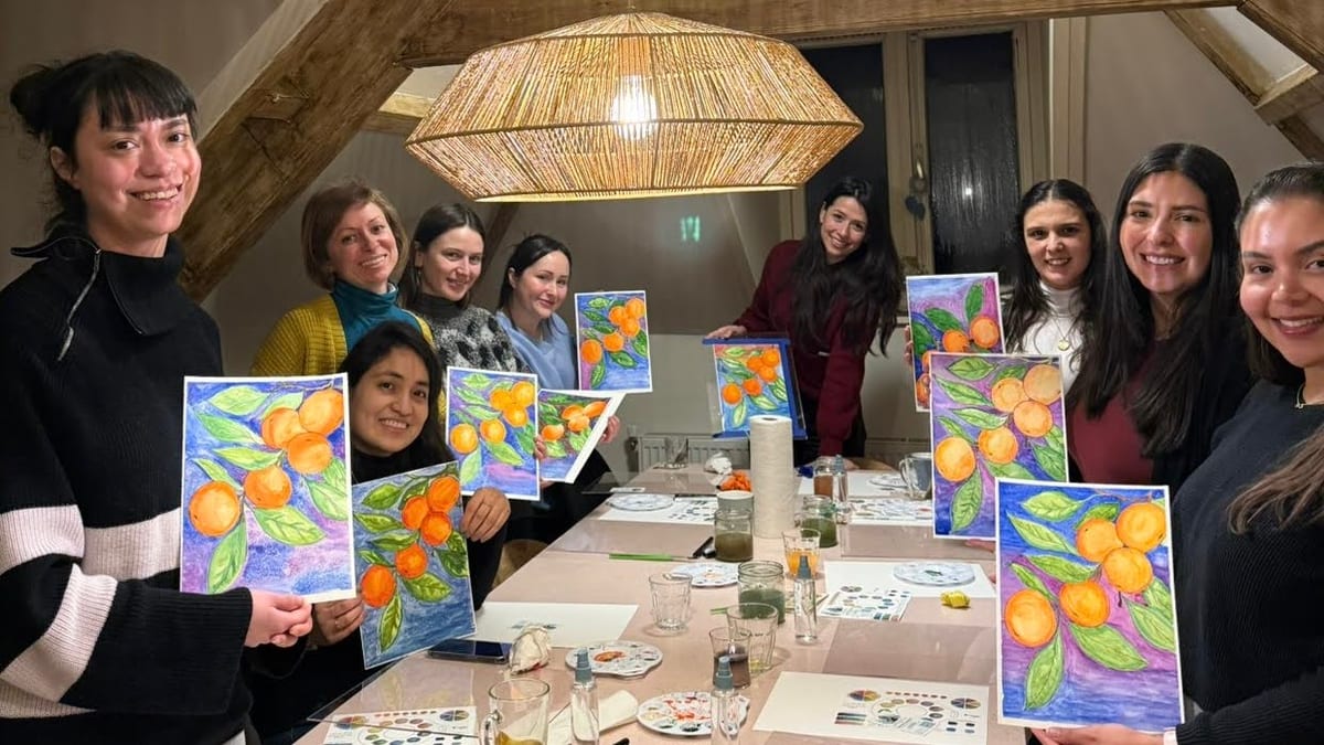 A happy group holding up their finished watercolour paintings of oranges