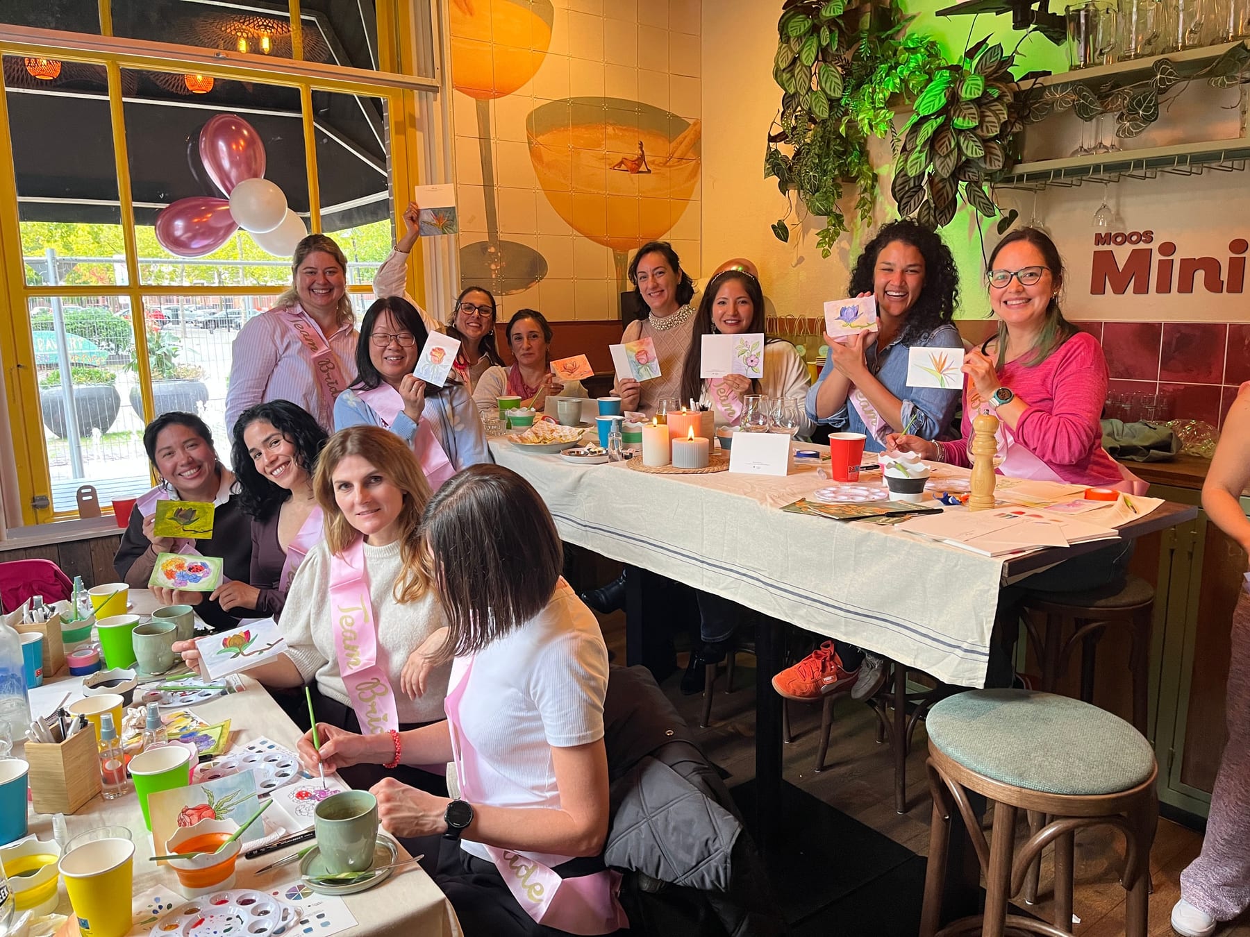 A bachelorette party group in Utrecht holding up the watercolour cards they painted
