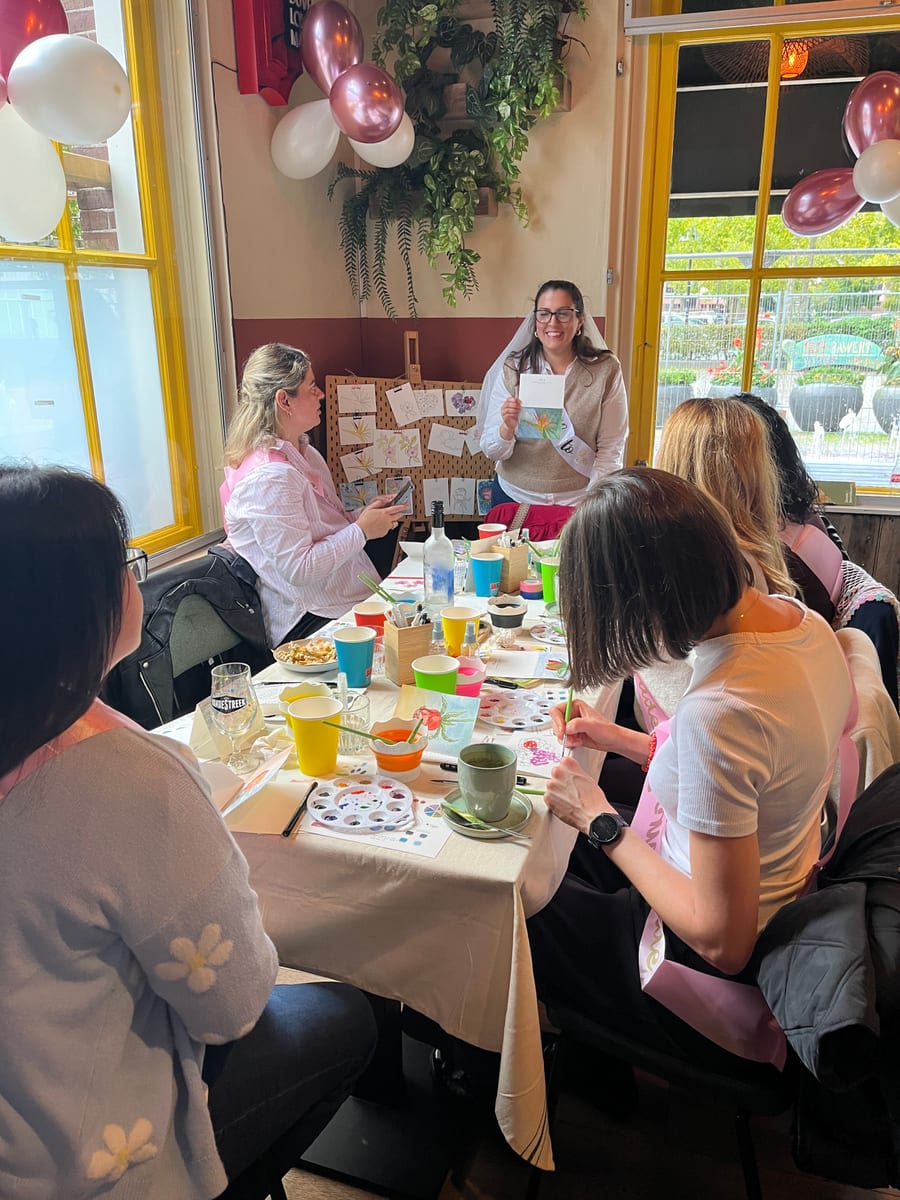A row of women painting watercolour cards together at a long table
